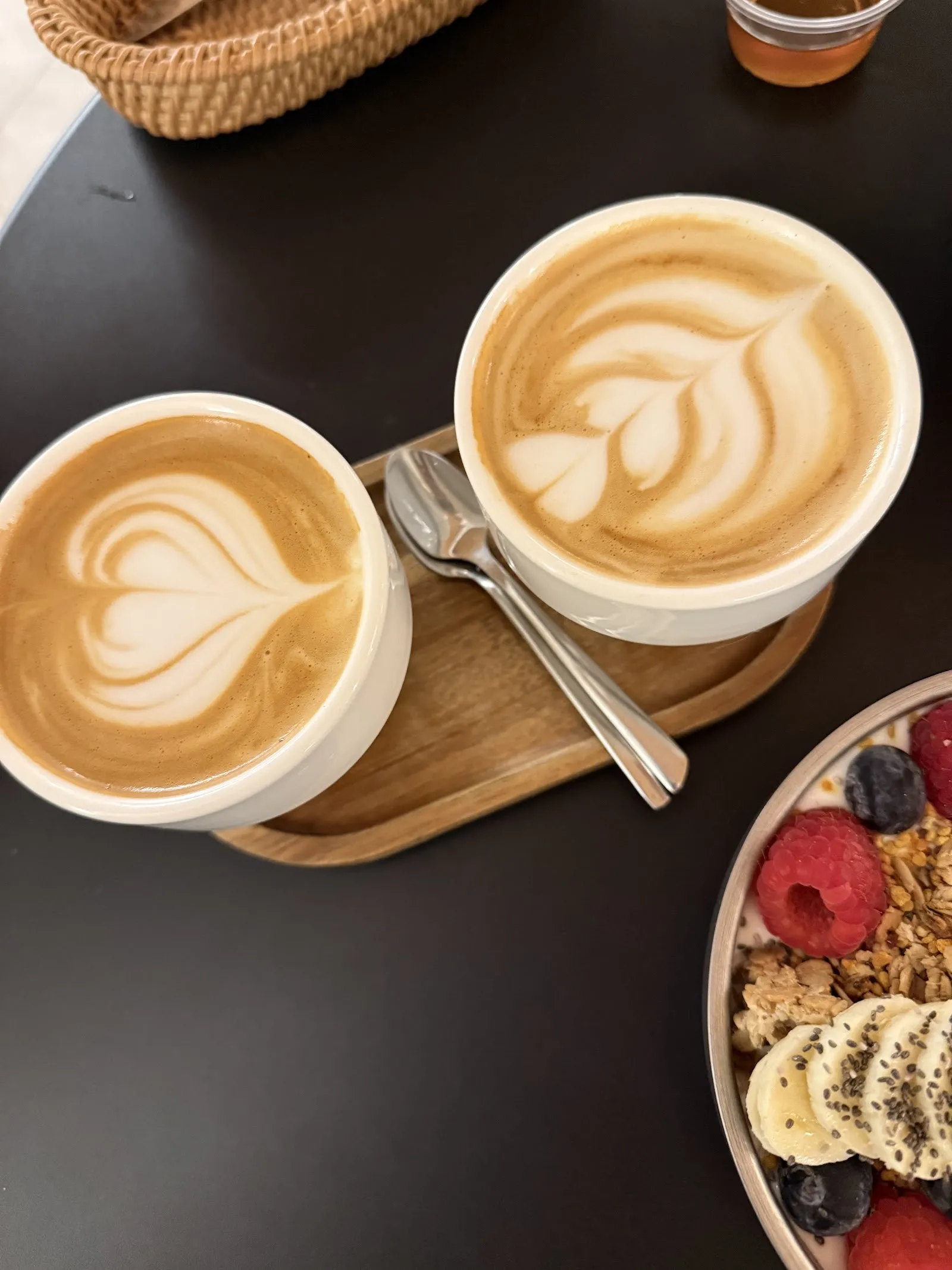 Dos cafés con leche y un bowl de fruta con granola